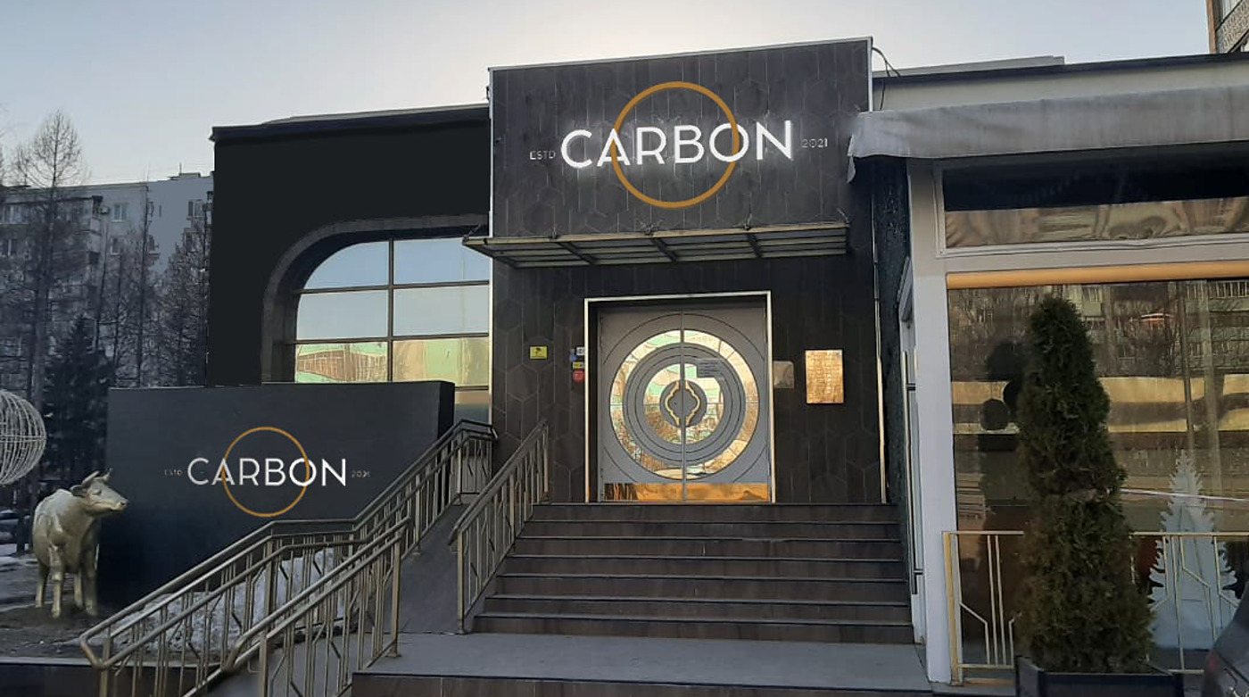 Вывеска CARBON со знаком-кругом на тёмном фасаде ресторана