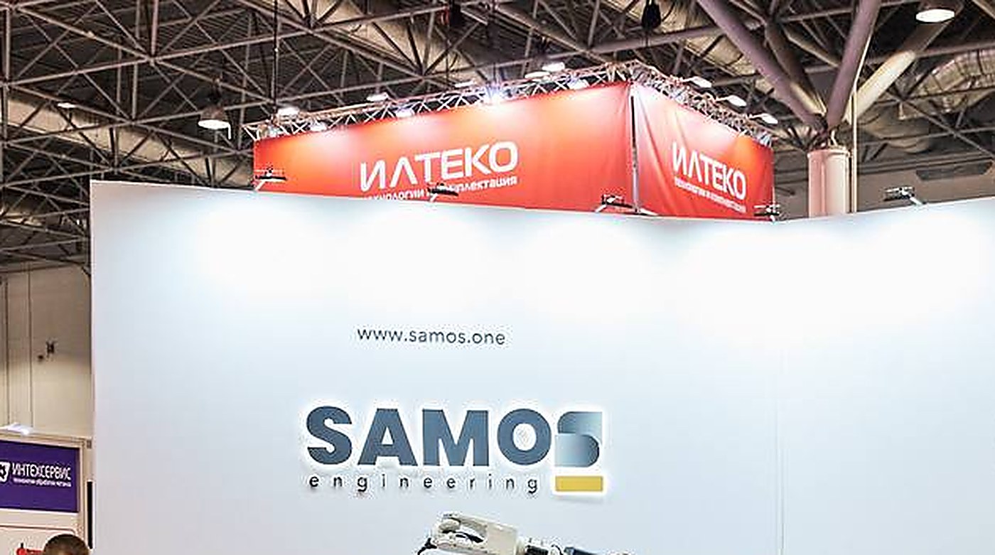 Стенд SAMOS engineering на отраслевой выставке: белая стена со знаком и адресом сайта