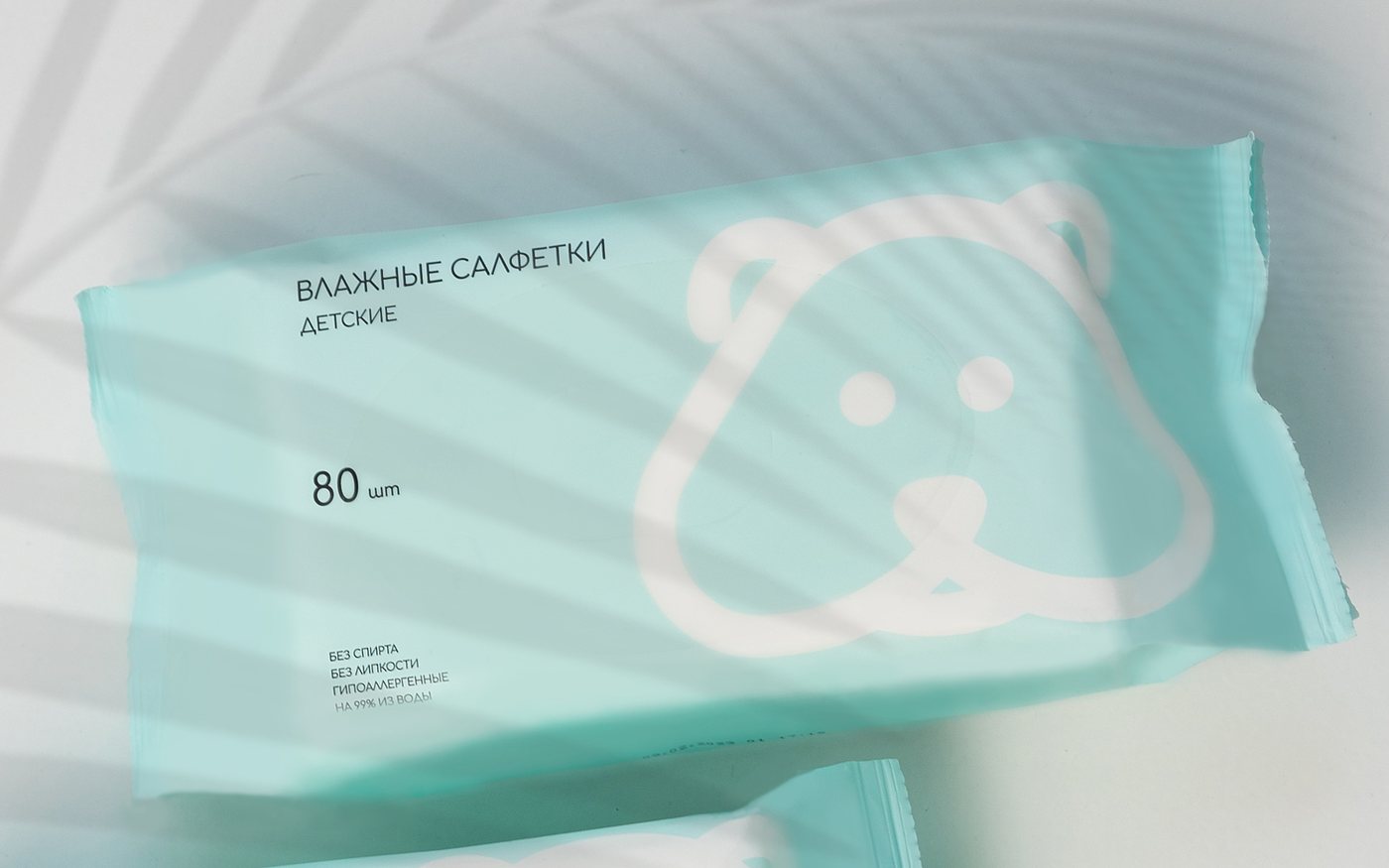 Пачка детских влажных салфеток мятного цвета, на упаковке тень от жалюзи