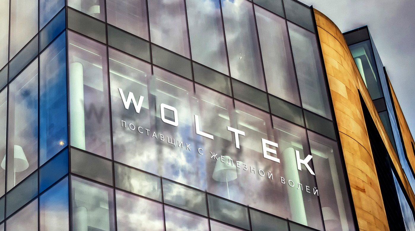 Примерка знака WOLTEK на стеклянном фасаде здания